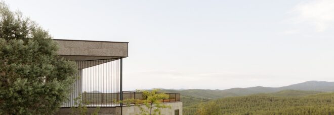 A building overlooks a mountain and forest range