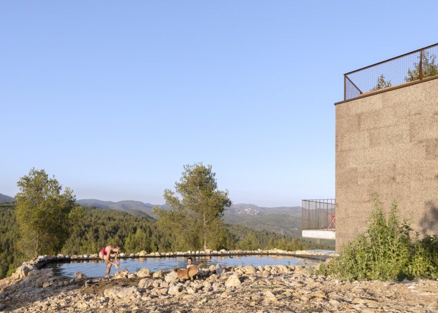 A stone building with a pool that overlooks a forest and mountains