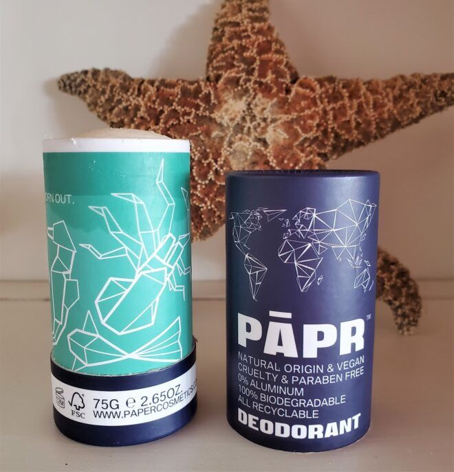 A blue deodorant tube with the dark blue cap sitting next to it