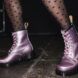 A person in sheer black tights wearing a pair of pink Dr. Martens.