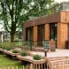 Corner view of wood clad house on a wooden deck next to benches that have in-built planters