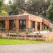 Edge view of wooden house with an external staircase leading to open rooftop garden