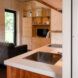 View looking past kitchen towards living spaces with wood clad interior and in-built wooden shelves