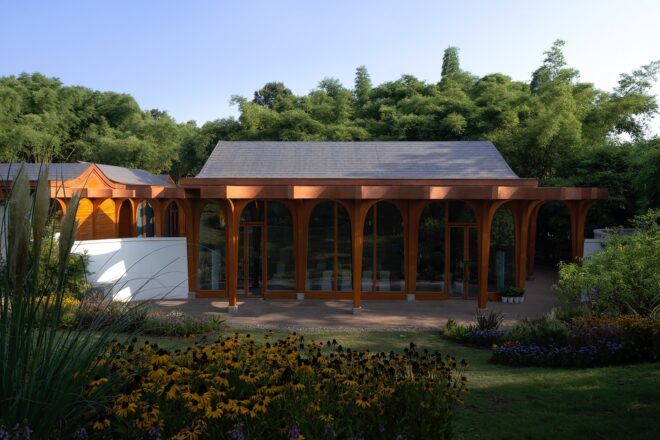 A wooden building sits merged with the green scenery that surrounds it
