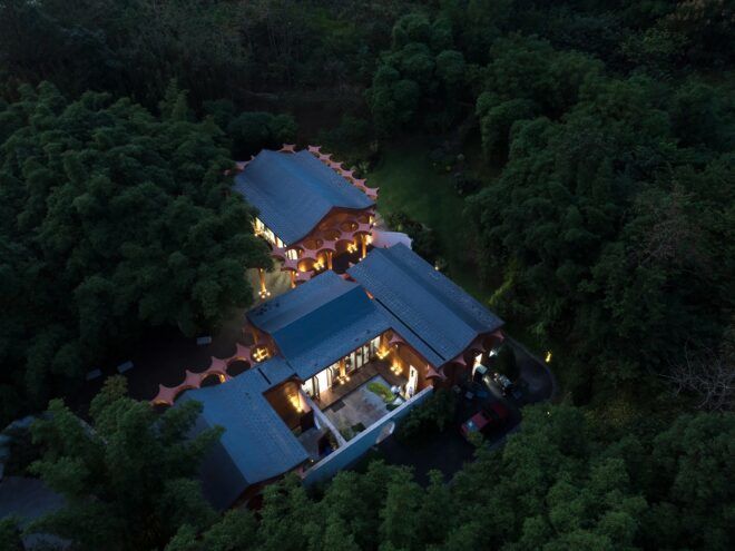 A building hidden in a forest lit up with lights at night