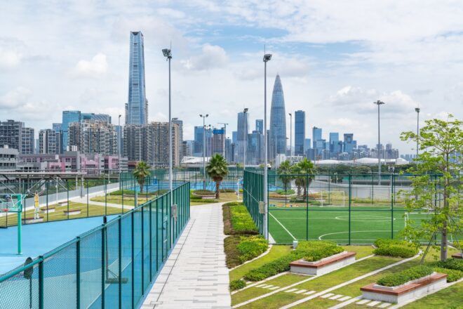 A silhouette of the city skyline in the background while fenced sport courts are in the foreground