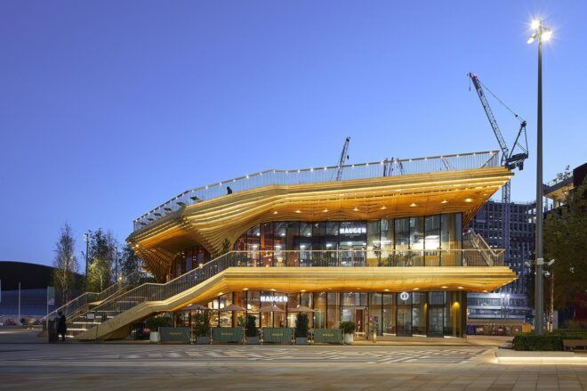 The exterior of a two-level wood pavilion at dusk.
