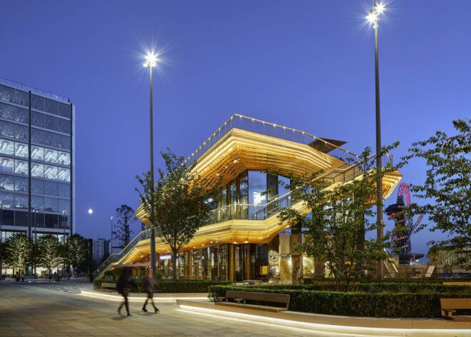 The exterior of a two-level wood pavilion at dusk.