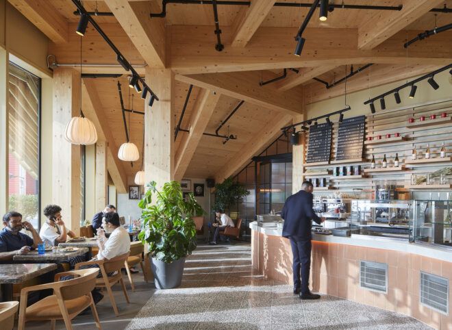 A cafe with a wood ceiling and large windows bringing in natural light.