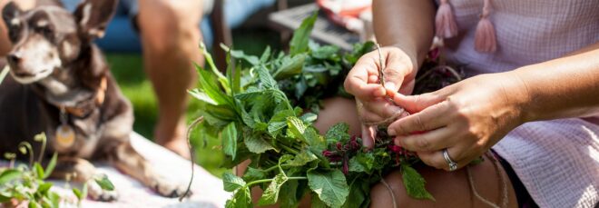 Hands weaving a wreathe made of herbs