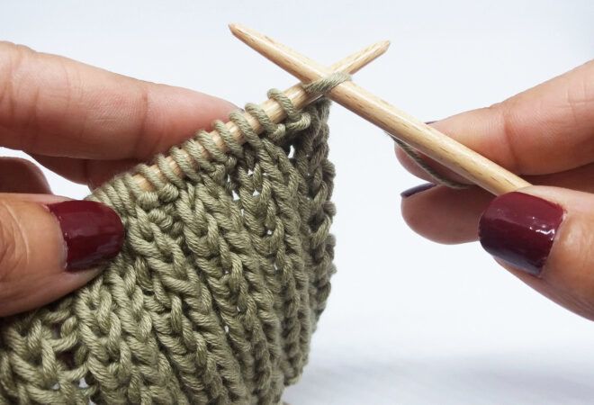 A pair of hands knitting with green yarn.