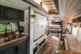 The inside of the bus has a kitchen space with a sink and opposite it is a counter space