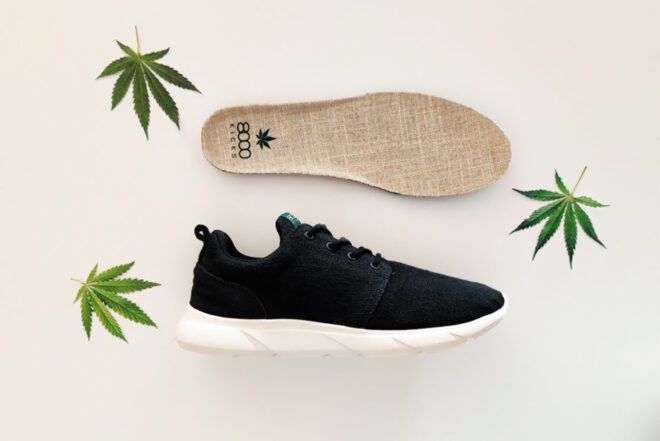 A pair of black and white sneakers surrounded by three hemp leaves.