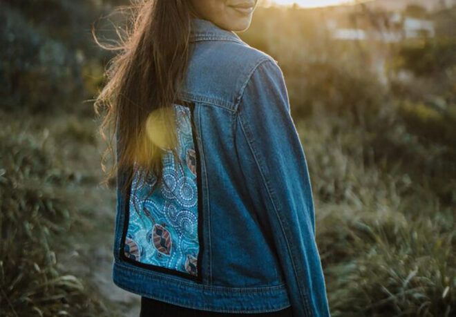 A person wearing a colorful designed denim jacket.