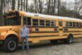 A man is standing next to a yellow school bus