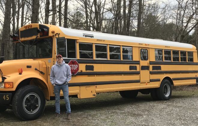 A man is standing next to a yellow school bus