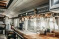 A counter has a laptop and mason jar lighting facing a window