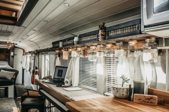 A counter has a laptop and mason jar lighting facing a window