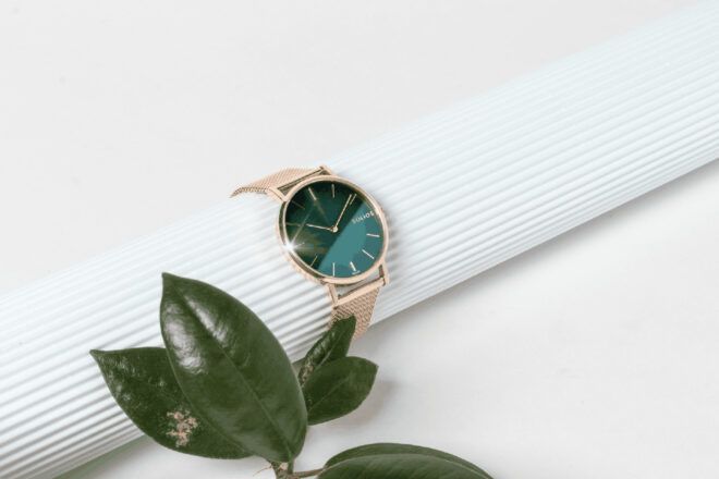 A green watch next to some leaves.