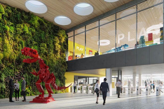 The lobby of a LEGO factory, with a large red LEGO dinosaur statue.