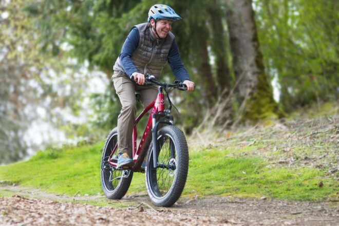 A man wearing a blue helmet and puff vest riding a red bike