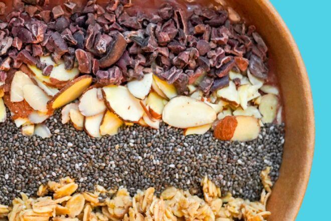 A bowl filled with chocolate syrup, almond, chia seeds and granola