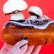 A hand holding a donut that is covered in edible mushroom creations