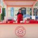 A pink bakery stand with a woman wearing a red apron standing inside of it