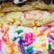 Close up of a ice cream cookie sandwich with sprinkles covering the sides of it