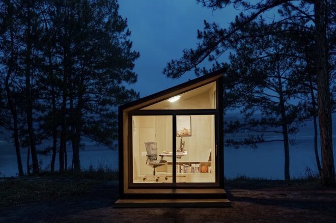 A pod with a slanting roof with the light on in the night