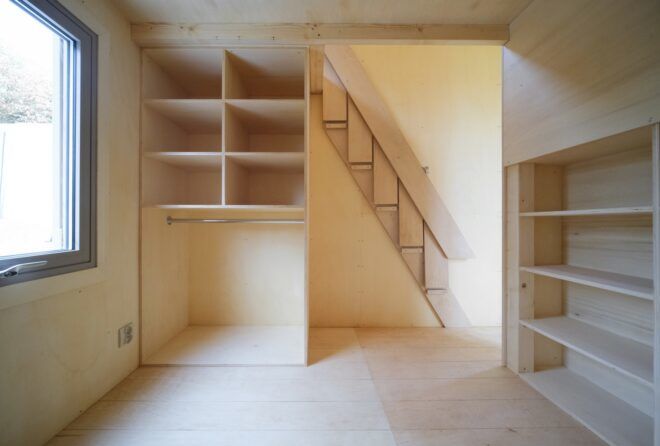 A foldable staircase leading to the upstairs and wooden shelving against the walls