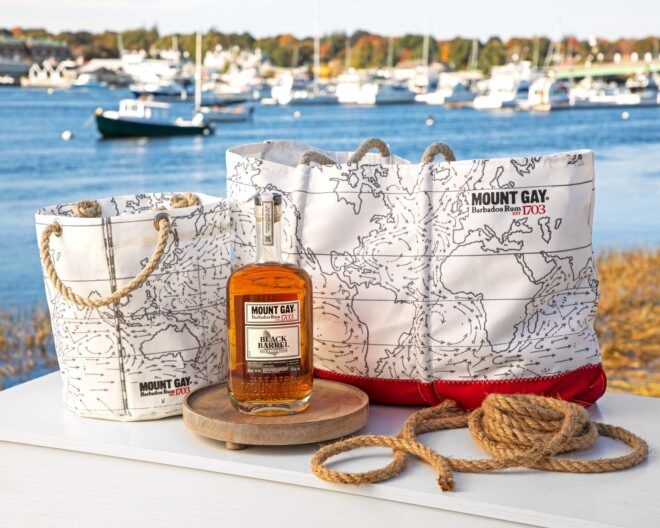 A tote bag and beverage bucket with a alcohol beverage sitting in between them and some rope on the side