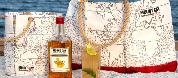A beverage bucket, tote bag, bottle of alcohol and a cup of alcoholic beverage
