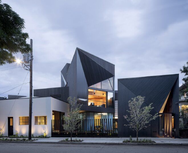 A geometric blue building that has its lights turned on inside