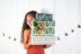 A girl with curly hair holding three boxes of gifts stacked on top of each other