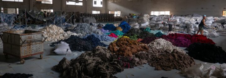 A large warehouse with piles and piles of clothes on the ground