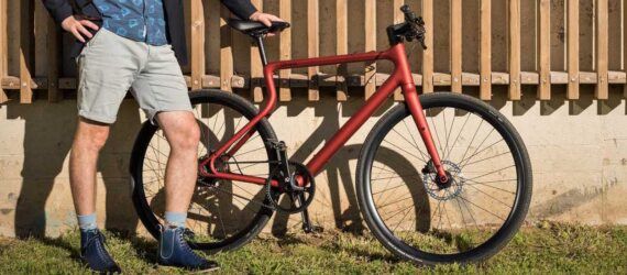 A person standing next to a red bike.