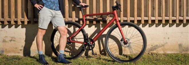 A person standing next to a red bike.