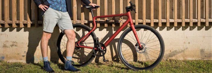 A person standing next to a red bike.