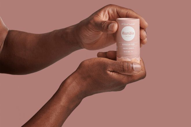 A pair of hands holding a pink stick of deodorant.