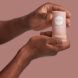 A pair of hands holding a pink stick of deodorant.