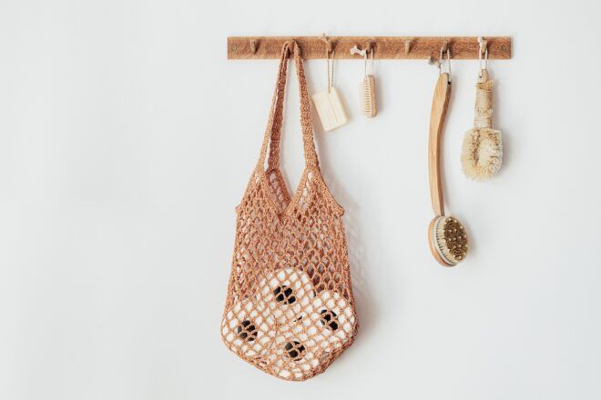 A mess net, soap, back scrubber and sink scrubber all hanging on a wooden hanger