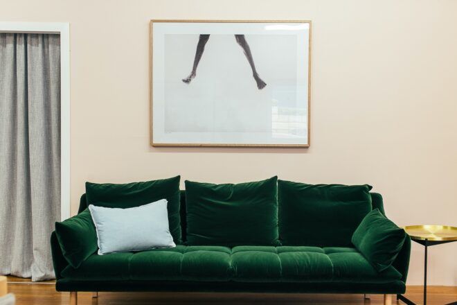 A velvet green sofa against a cream wall