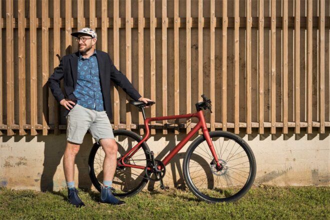 A person standing next to a red bike.