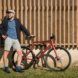 A person standing next to a red bike.
