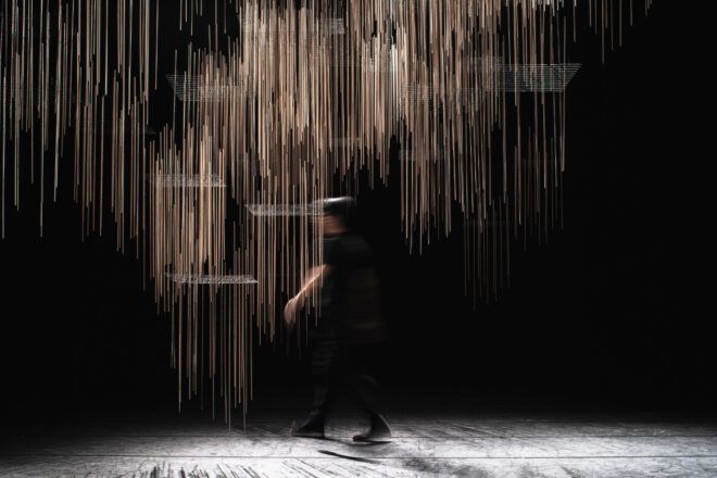 Long exposure image of an individual walking on-stage behind the installation