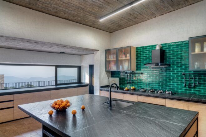 A kitchen room with a black tile island with a sink in the island as well