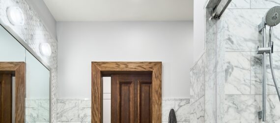 The inside of a bathroom with a shower head on the right and a part of the door on the left