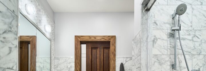 The inside of a bathroom with a shower head on the right and a part of the door on the left