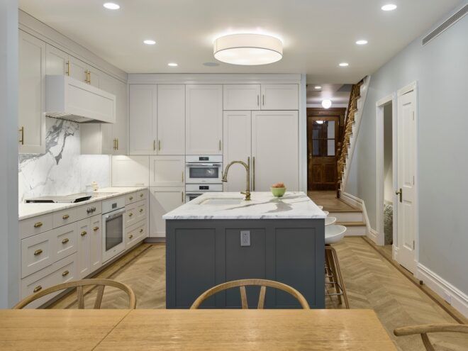 A kitchen area with a granite island and white cabinets